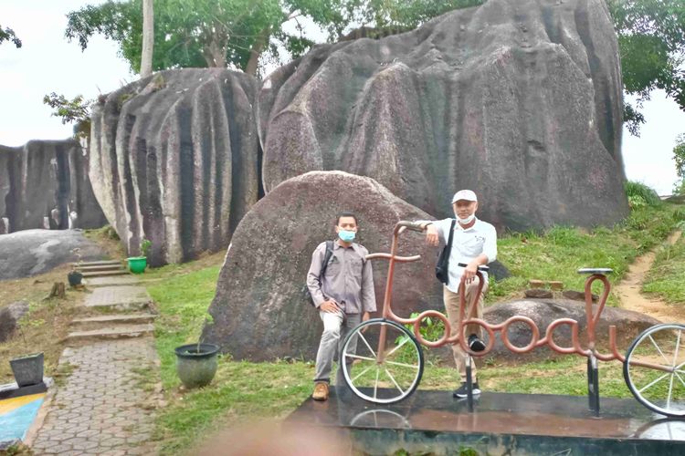 Pengunjung berpose dengan replika sepeda di gugusan batu belimbing, Toboali, Bangka Selatan, Rabu (23/6/2021).
